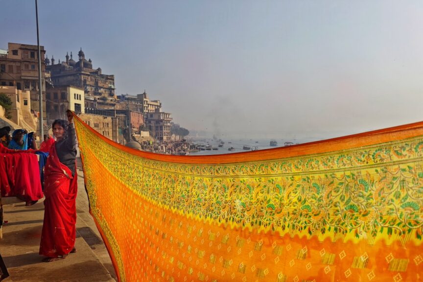 Woman displaying handwoven silk fabric by the Ganges in Varanasi
