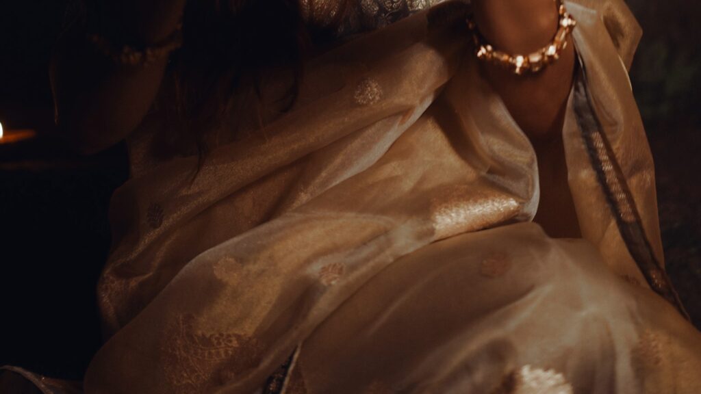 Woman in a festive Banarasi silk saree holding a tray of lit diyas for Diwali