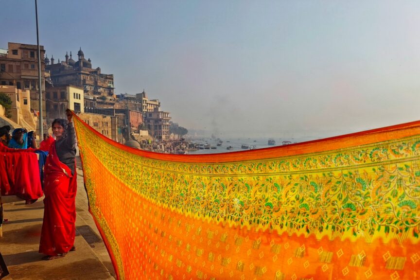 Woman in red silk saree with handwoven fabric by the Ganges in Varanasi